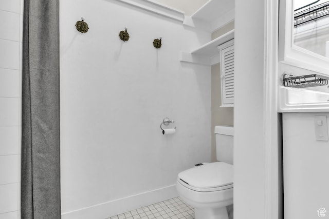 bathroom featuring tile patterned flooring, toilet, and baseboards