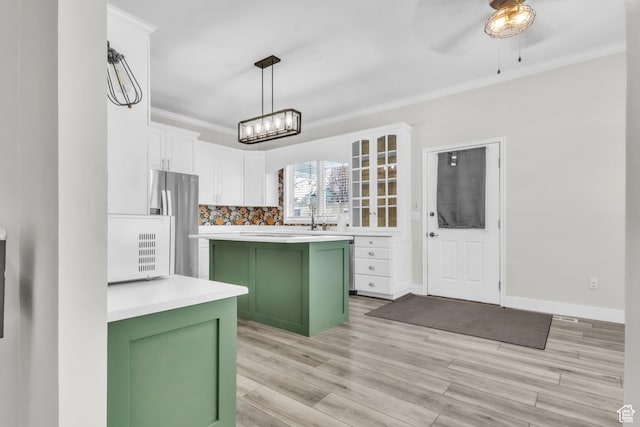 kitchen with light countertops, white cabinets, ornamental molding, freestanding refrigerator, and green cabinetry