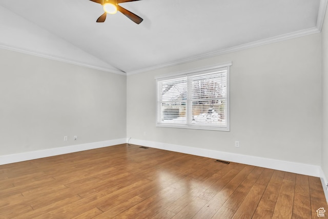 spare room featuring hardwood / wood-style floors, vaulted ceiling, crown molding, and a ceiling fan