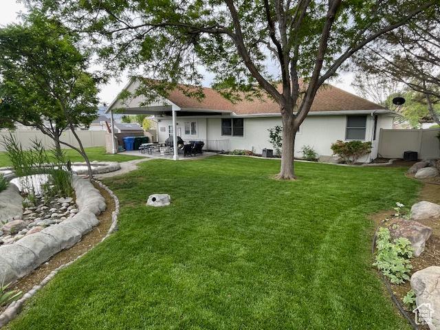 back of house featuring a patio area, stucco siding, fence, and a yard