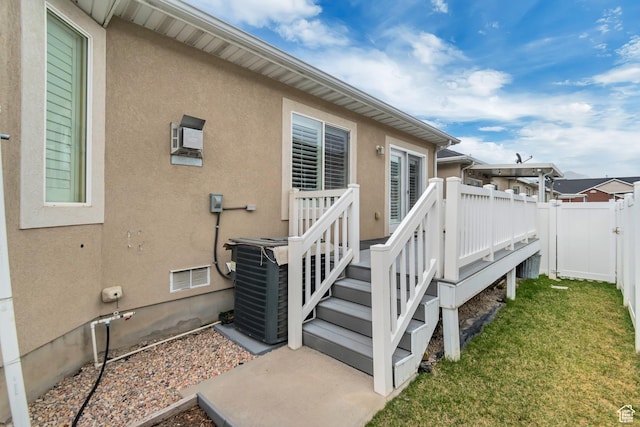 exterior space featuring stucco siding, fence, a deck, visible vents, and a lawn