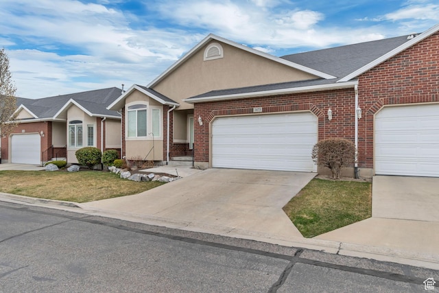 single story home with stucco siding, a garage, brick siding, and concrete driveway