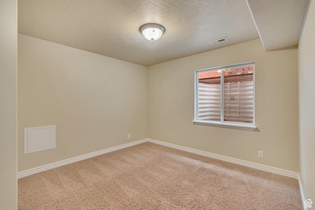 carpeted empty room featuring baseboards, a textured ceiling, and visible vents