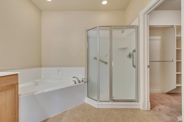 full bath with tile patterned floors, a walk in closet, a garden tub, and a shower stall