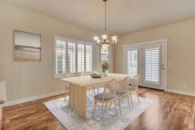dining area with baseboards, wood finished floors, and a notable chandelier