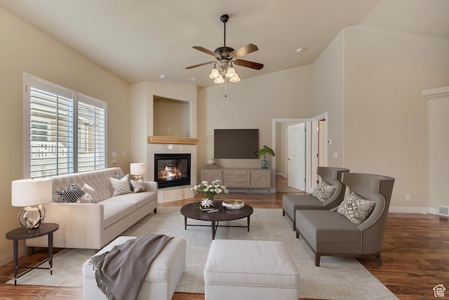 living room with visible vents, light wood-style flooring, baseboards, a fireplace, and a ceiling fan