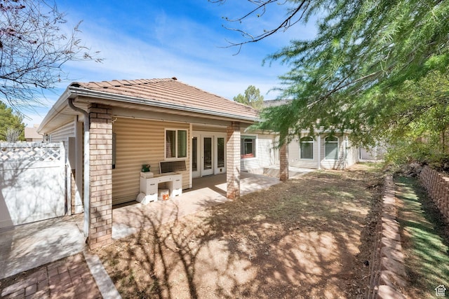 rear view of house with french doors, a tiled roof, fence, and a patio area