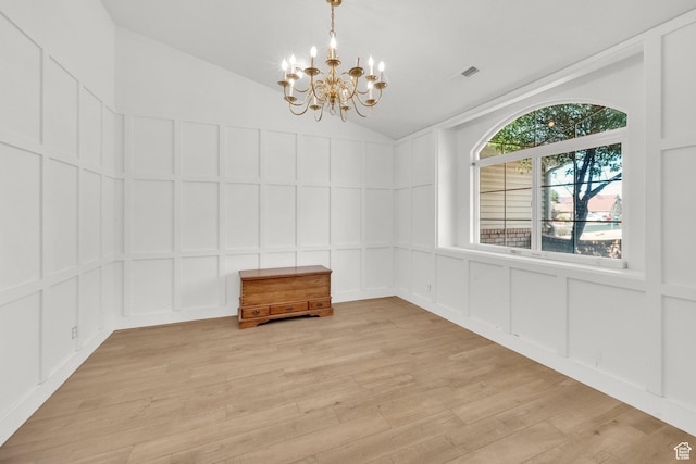 unfurnished dining area featuring vaulted ceiling, a chandelier, a decorative wall, visible vents, and light wood-style floors