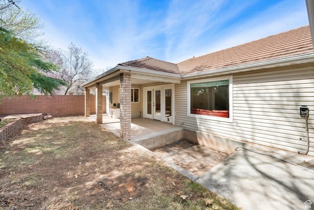 rear view of house with french doors, a tiled roof, fence, and a patio area