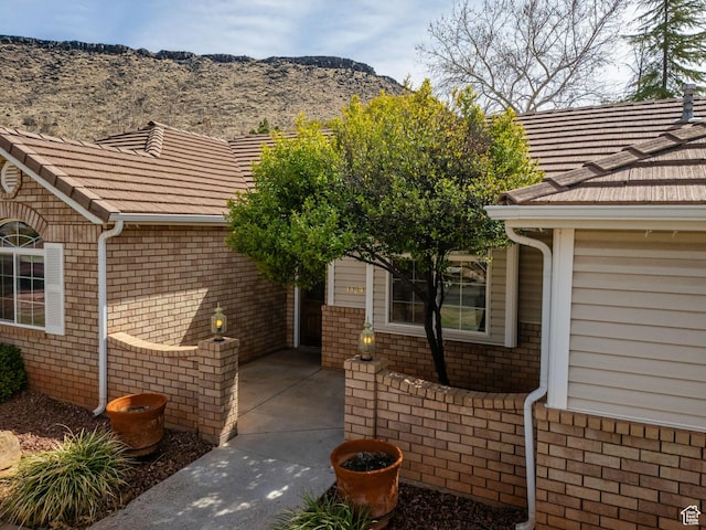view of side of property with a mountain view, a tiled roof, and brick siding