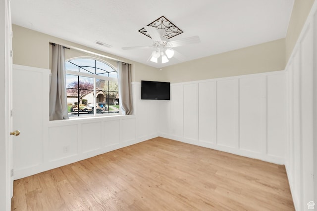 unfurnished room featuring a decorative wall, visible vents, ceiling fan, and light wood-type flooring