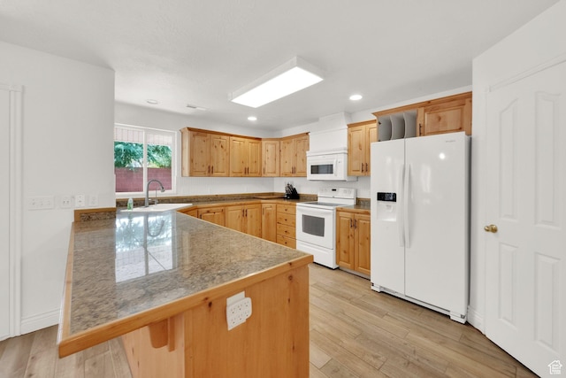 kitchen with light wood-type flooring, a sink, a peninsula, and white appliances