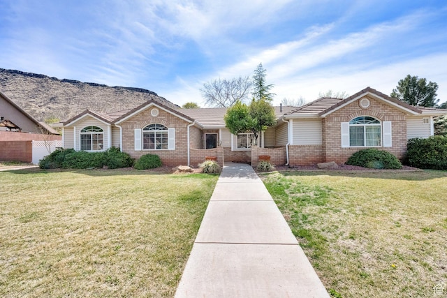 single story home featuring brick siding, fence, a tiled roof, and a front yard