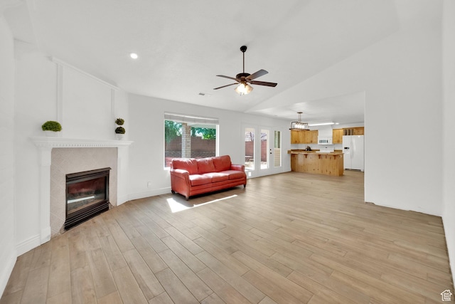 unfurnished living room with lofted ceiling, baseboards, ceiling fan, light wood-style flooring, and a glass covered fireplace