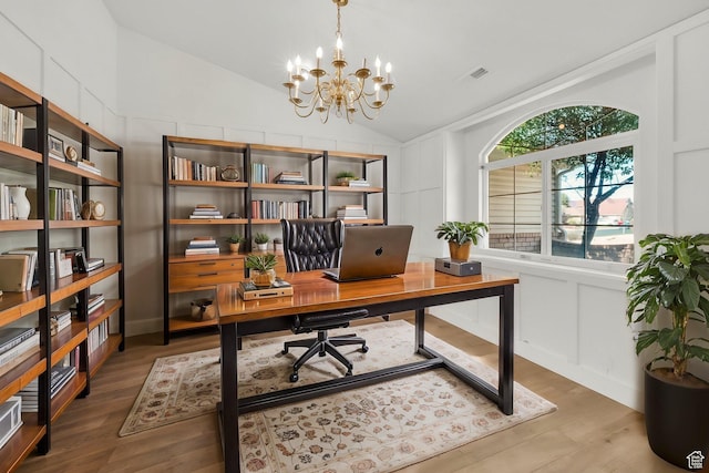 home office with vaulted ceiling, wood finished floors, a decorative wall, and a chandelier