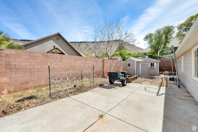 view of patio with an outdoor structure, a fenced backyard, and a shed