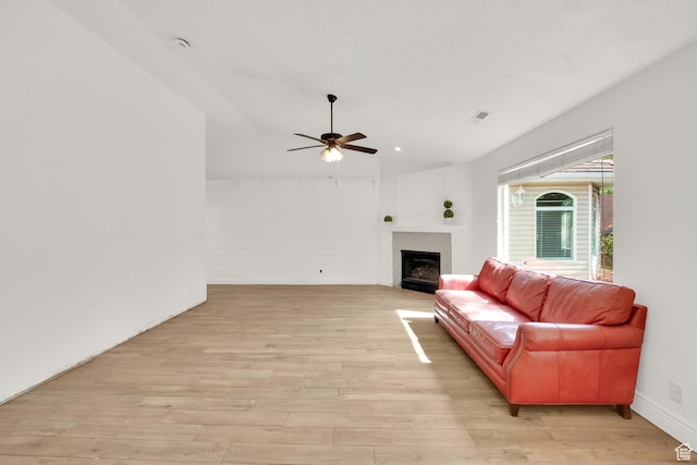 living area with visible vents, a fireplace, light wood-style flooring, and ceiling fan