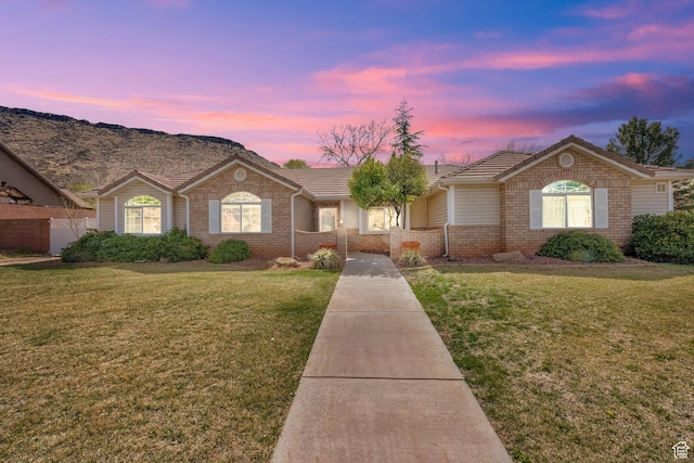 ranch-style home featuring brick siding, a front lawn, and a tile roof