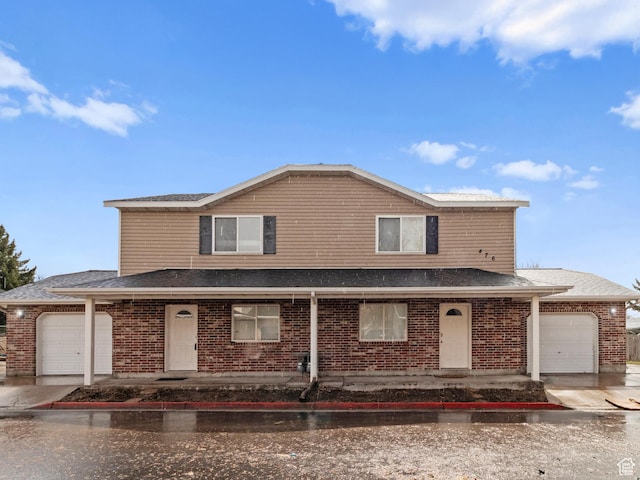 traditional home with brick siding, driveway, roof with shingles, and an attached garage