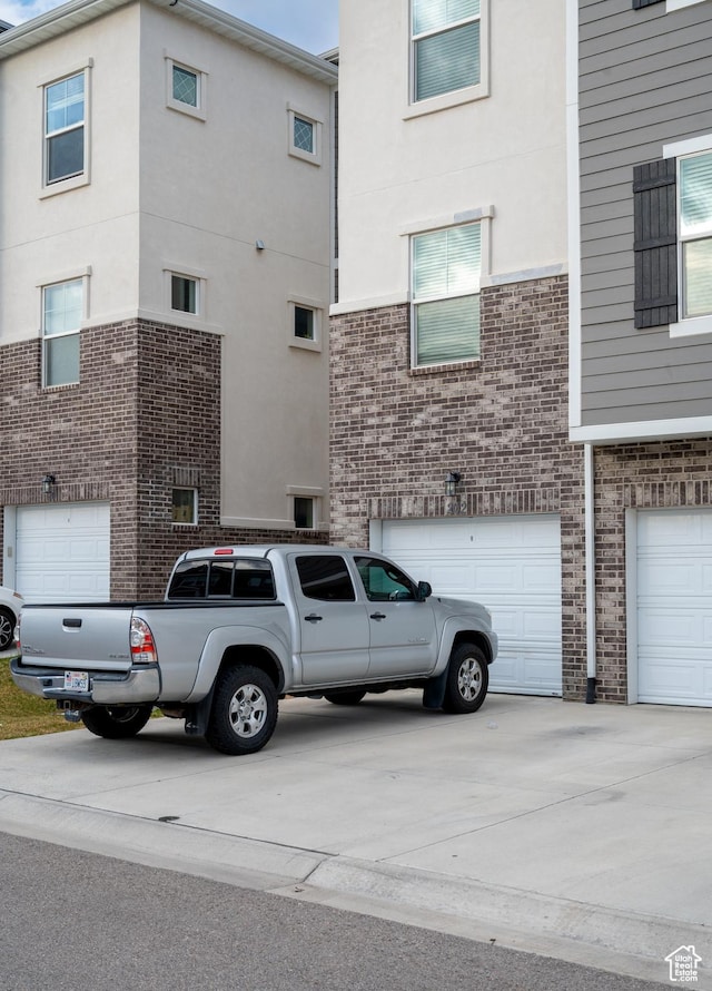 13091 S Newbridge Ln Unit F202, Herriman, UT 84096 - view of side of home featuring a garage, brick siding, and concrete driveway