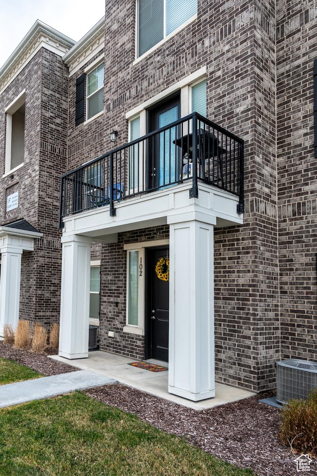 13091 S Newbridge Ln Unit F202, Herriman, UT 84096 - view of exterior entry with a balcony, brick siding, and central air condition unit