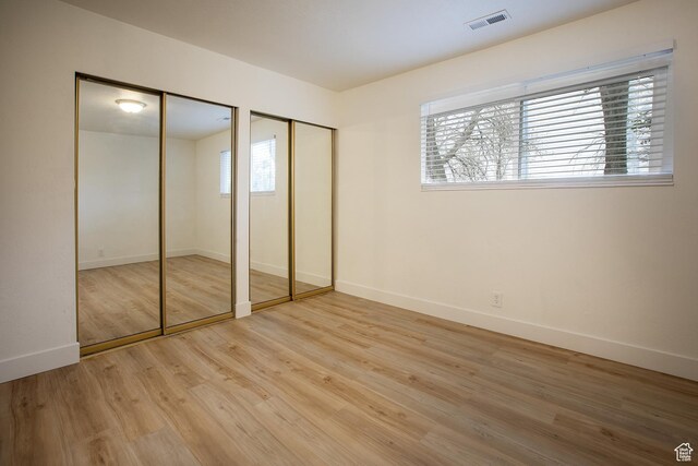 3510 S 300 E Unit E, South Salt Lake, UT 84115 - unfurnished bedroom featuring two closets, light wood-style floors, and baseboards