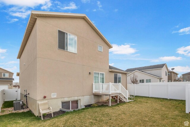 3414 S Melanie Cv W Unit 13, Magna, UT 84044 - back of property featuring stucco siding, central air condition unit, a fenced backyard, a gate, and a lawn