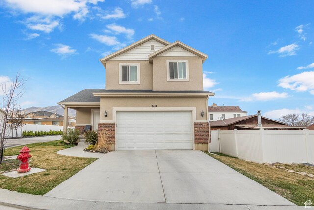 3414 S Melanie Cv W Unit 13, Magna, UT 84044 - view of front of house with stucco siding, fence, an attached garage, driveway, and brick siding