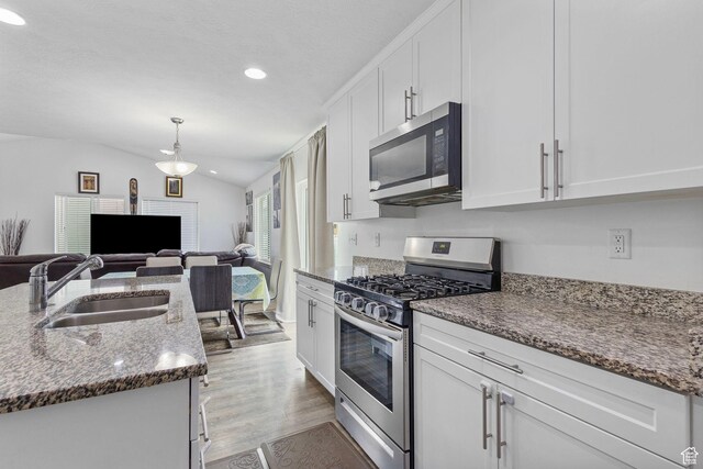 3414 S Melanie Cv W Unit 13, Magna, UT 84044 - kitchen with a sink, white cabinetry, appliances with stainless steel finishes, lofted ceiling, and dark stone countertops