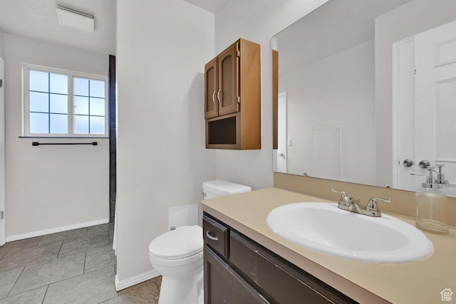bathroom with baseboards, toilet, and vanity