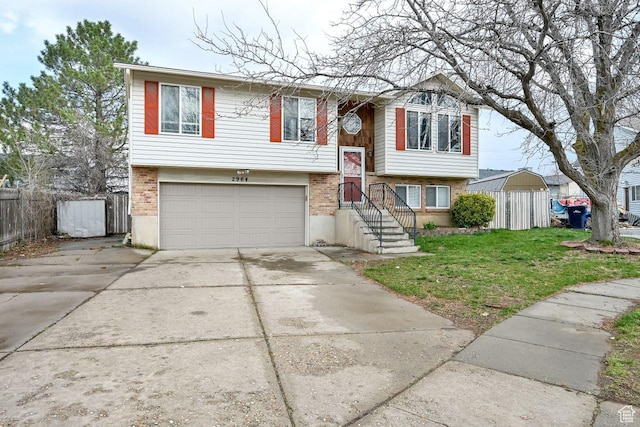 raised ranch featuring fence, an attached garage, brick siding, and concrete driveway