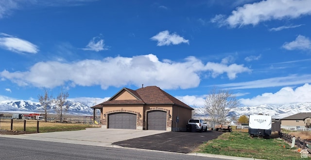 546 S Quirk St, Grantsville, UT 84029 - view of front of house featuring stucco siding, fence, aphalt driveway, a mountain view, and a garage