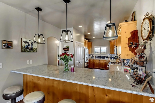 546 S Quirk St, Grantsville, UT 84029 - kitchen featuring brown cabinetry, arched walkways, appliances with stainless steel finishes, and a peninsula