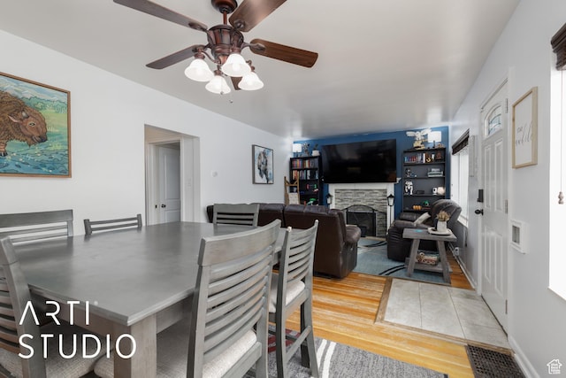 2209 Van Buren Ave, Ogden, UT 84401 - dining area featuring a fireplace, ceiling fan, visible vents, and light wood-style floors
