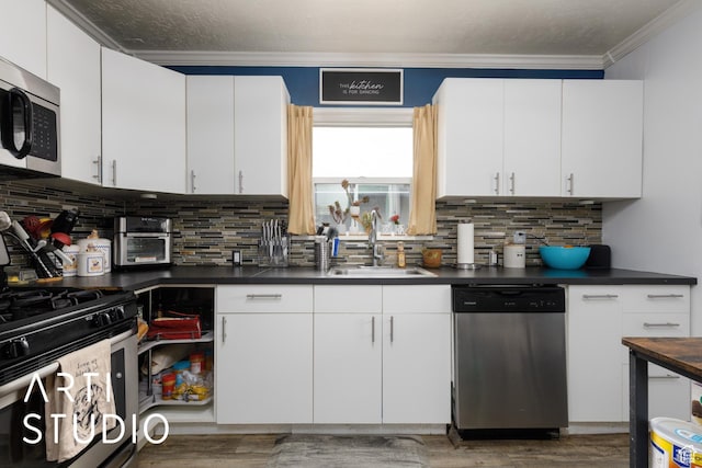 2209 Van Buren Ave, Ogden, UT 84401 - kitchen featuring light wood-type flooring, ornamental molding, a sink, dark countertops, and appliances with stainless steel finishes