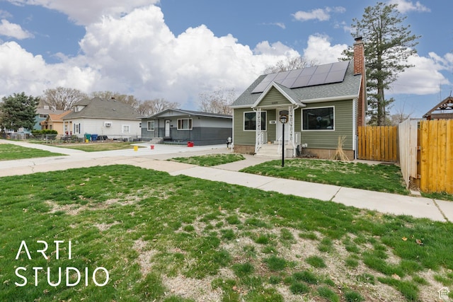2209 Van Buren Ave, Ogden, UT 84401 - bungalow-style house featuring a front lawn, roof mounted solar panels, a chimney, and fence