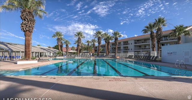 community pool with fence, a residential view, and a patio area