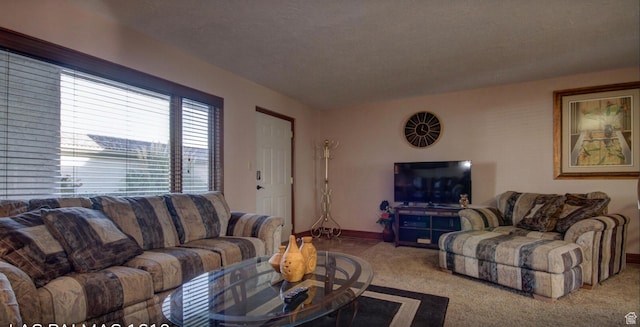living area featuring carpet flooring, baseboards, and a textured ceiling