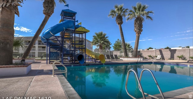 pool with playground community, a water slide, and fence