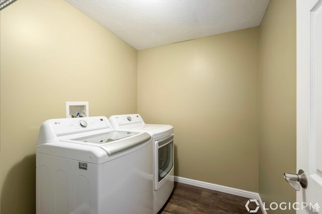 clothes washing area with separate washer and dryer, laundry area, dark wood finished floors, and baseboards