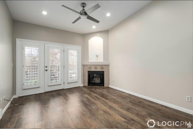 unfurnished living room with a ceiling fan, baseboards, dark wood-style flooring, a tiled fireplace, and visible vents
