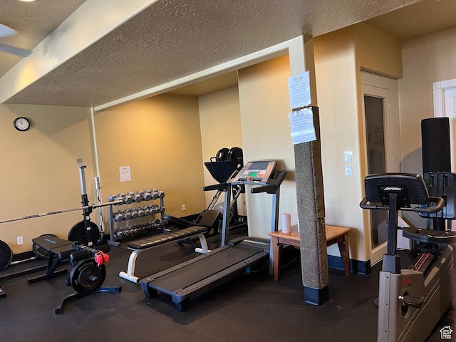 gym featuring a textured ceiling and baseboards