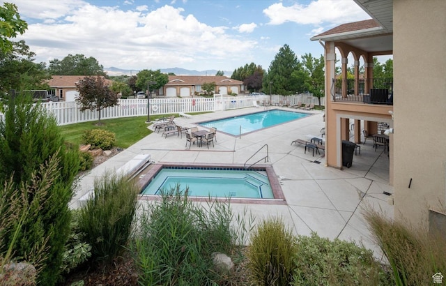 pool with a mountain view, fence, a community hot tub, and a patio