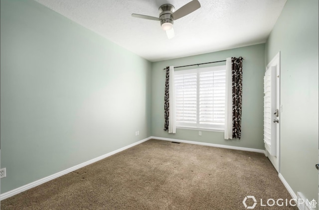 carpeted empty room with a textured ceiling, baseboards, and a ceiling fan