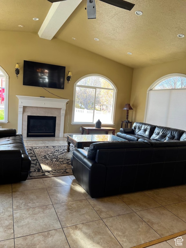 living room with a textured ceiling, a tiled fireplace, light tile patterned floors, and plenty of natural light