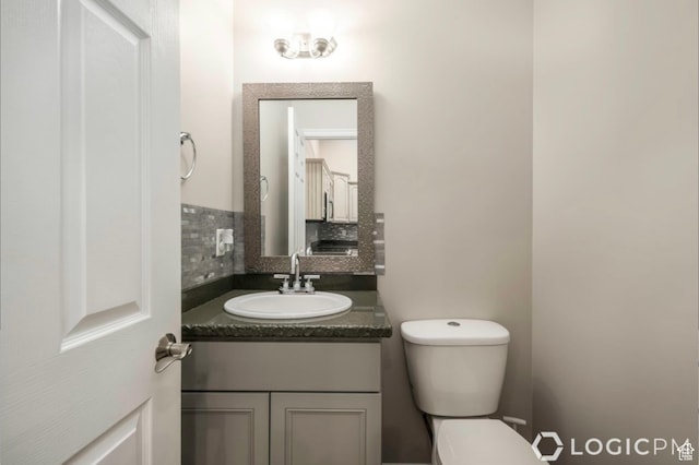 half bath with toilet, backsplash, and vanity