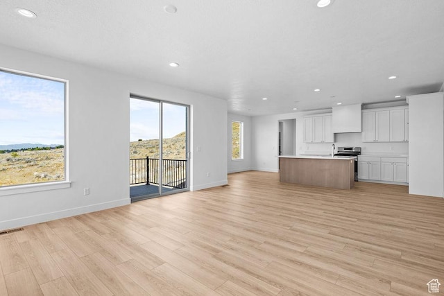 3666 W 2110 S Unit 103, Syracuse, UT 84075 - unfurnished living room featuring recessed lighting, baseboards, a sink, light wood finished floors, and visible vents