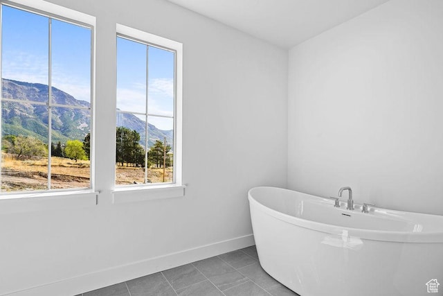3666 W 2110 S Unit 103, Syracuse, UT 84075 - bathroom featuring a freestanding bath, baseboards, a mountain view, and tile patterned floors