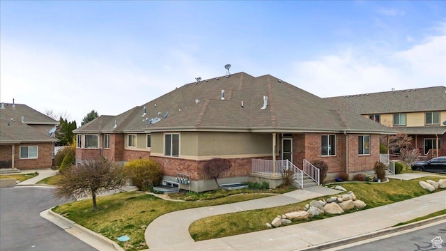 view of front facade featuring brick siding, a front lawn, and roof with shingles