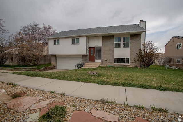 split foyer home featuring a chimney, an attached garage, fence, and brick siding